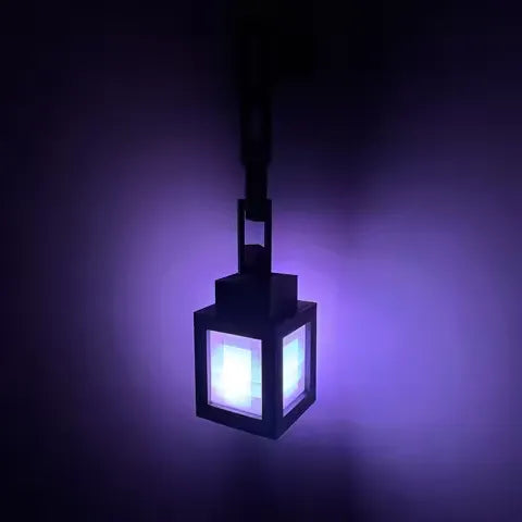 Lámpara farol LED pixel colgada de su cadena en la pared, iluminada en color violeta